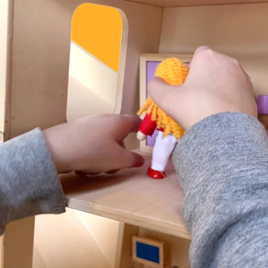 jongen-speelt-met-poppenhuispop-in-speelboom Jongen speelt met poppenhuispop in deze kinderkast met ramen en poorten op schaal.