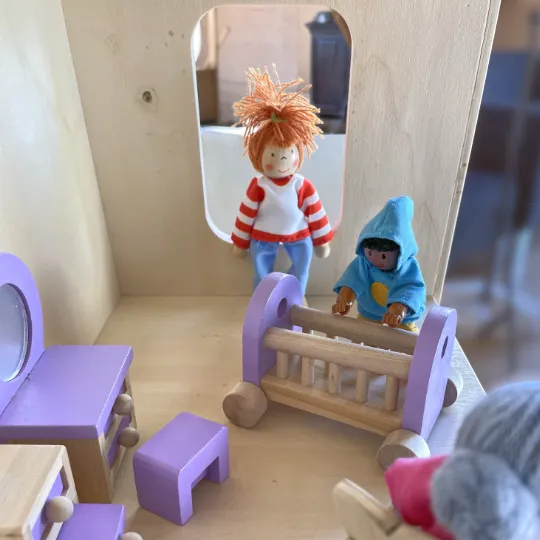 Baby Room Een jongens-poppetje buigt over de wieg van zijn poppe-zusje in de babykamer in houten poppenhuis Play3 Benoë.