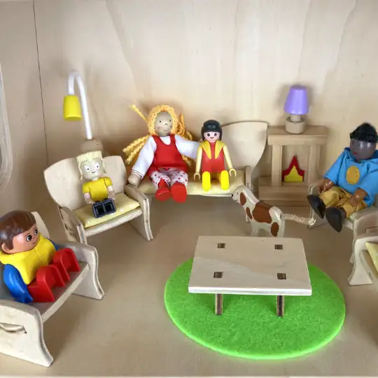 Samengestelde poppenfamilie Poppetjes van 7 verschillende merken zitten gezellig in een kring in houten poppenhuis Play3 Benoë.