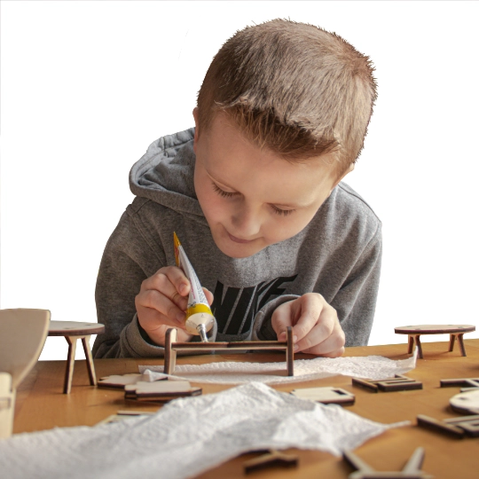 An 8 year old boy assembles a toy couch.